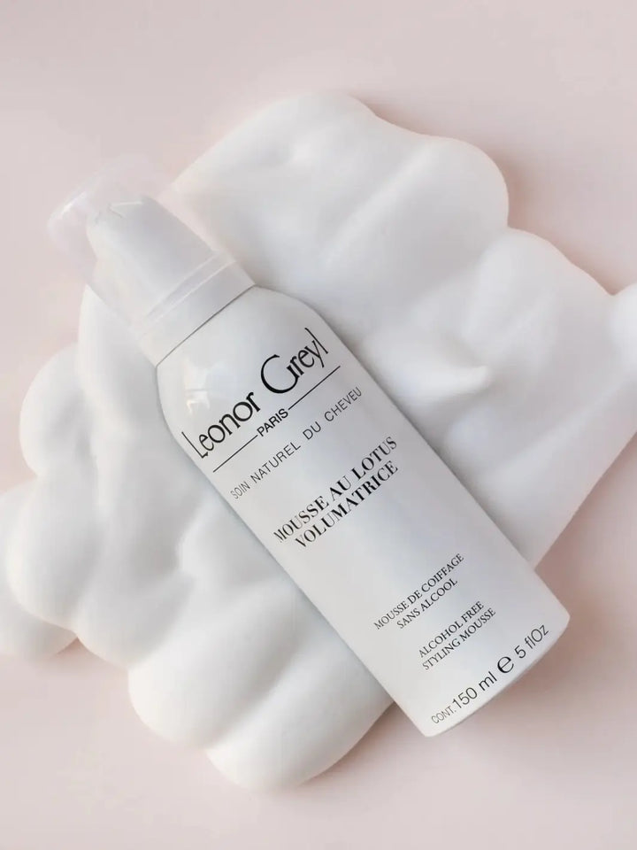Leonor Greyl 'Mousse au Lotus Volumatrice' 150ml bottle on a white towel with a pink background | Twentyseven Toronto