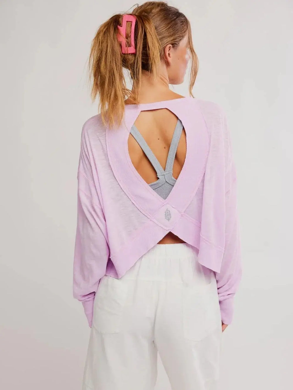 A rear view reveals the open cutout design and crisscross back straps of the Free People My Time Layer in Ultra Violet, layered over a grey sports bra | Twentyseven Toronto