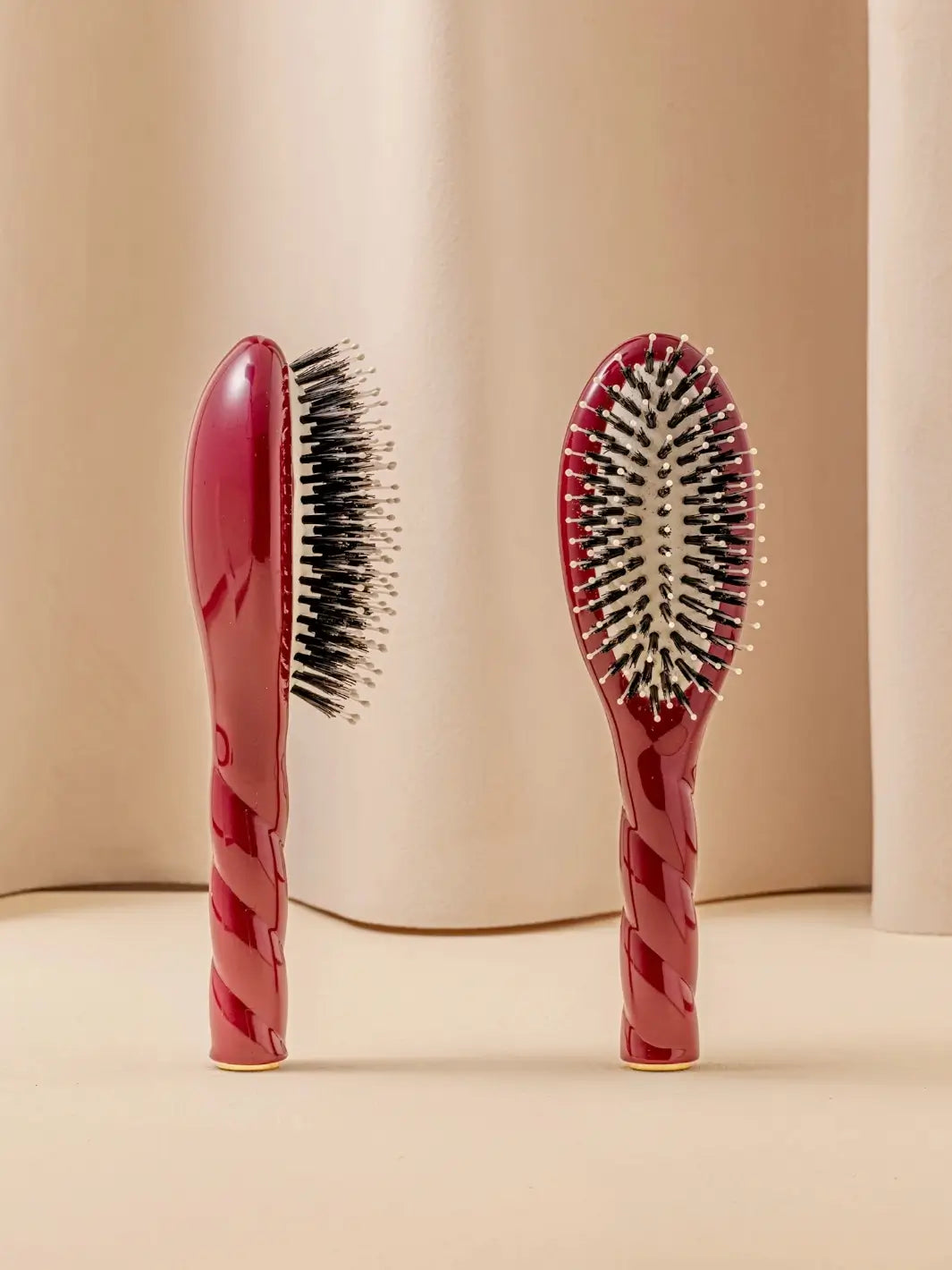 Front and side view of La Bonne Brosse N.03 Small The Essential Softness & Sensitive Scalp Brush in Cherry Red featuring a twisted ergonomic handle and natural boar and nylon bristles | Twentyseven Toronto
