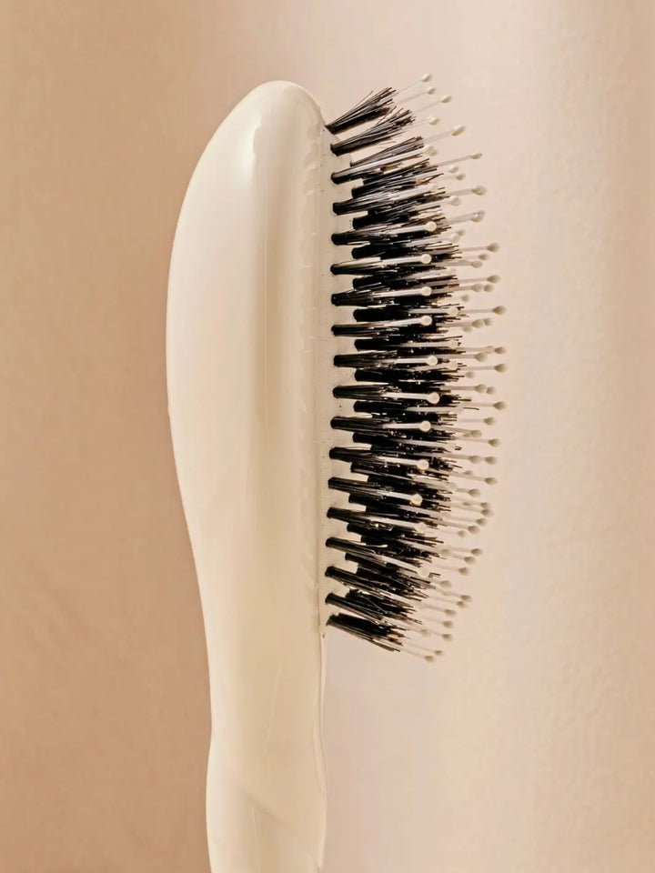 Close-up side view shot highlights the tiered bristle design of La Bonne Brosse N.03 Small The Essential Softness & Sensitive Scalp Brush in Creamy White | Twentyseven Toronto