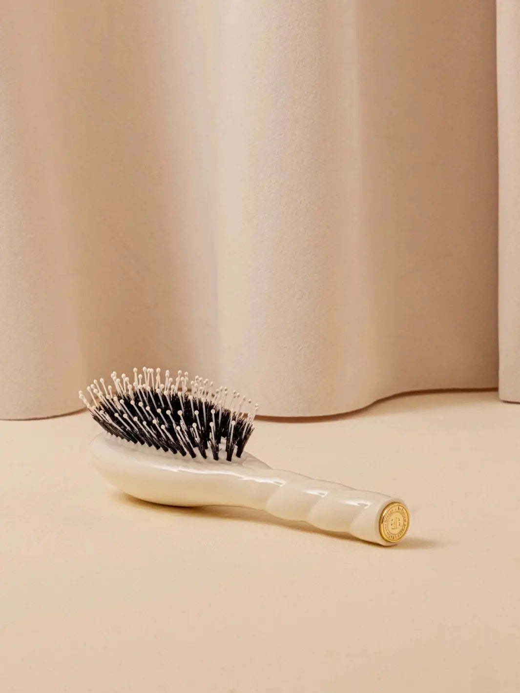 La Bonne Brosse N.03 Small The Essential Softness & Sensitive Scalp Brush in Creamy White resting on a neutral surface against a soft draped curtain background | Twentyseven Toronto