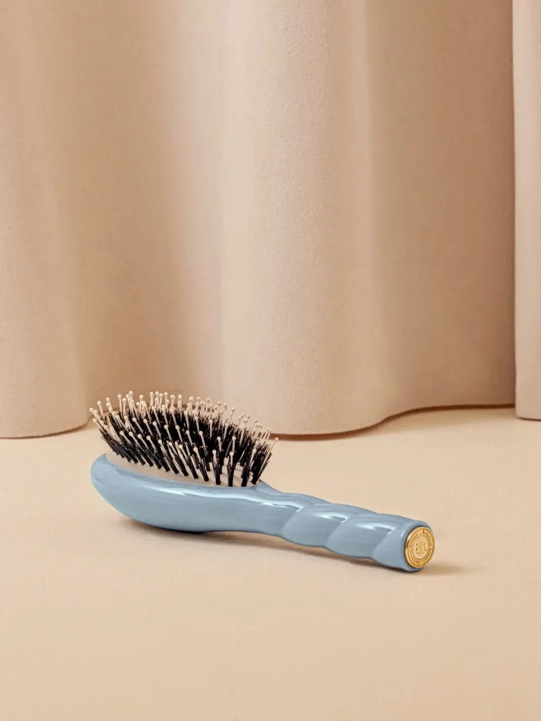 La Bonne Brosse N.03 Small The Essential Softness & Sensitive Scalp Brush in Light Blue resting on a neutral surface against a soft draped curtain background | Twentyseven Toronto