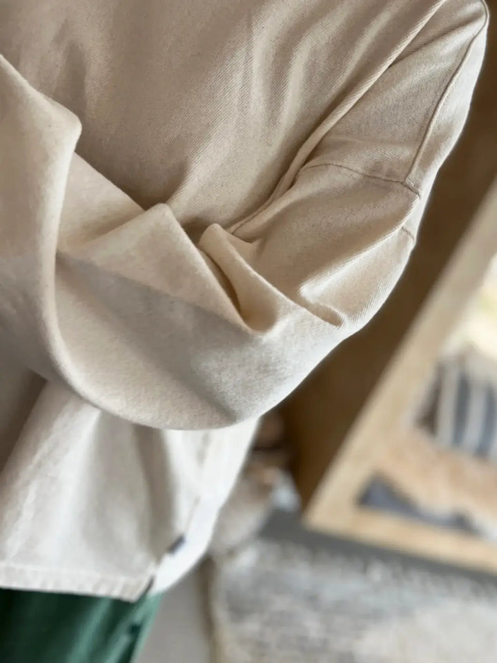 Close-up of cream 'Naturelle Tee' in 'Naturel' fabric with a blurred background | Twentyseven Toronto