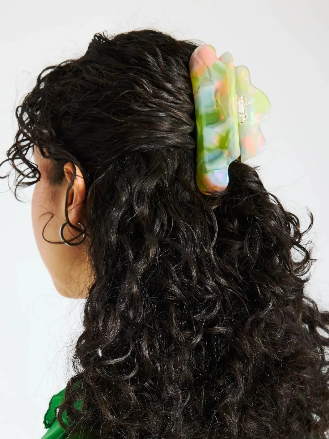 A model with long, dark curly hair styles a half-up look using the colorful, cloud-shaped CHUNKS Nimbus Claw Clip in Sherbet Jelly | Twentyseven Toronto