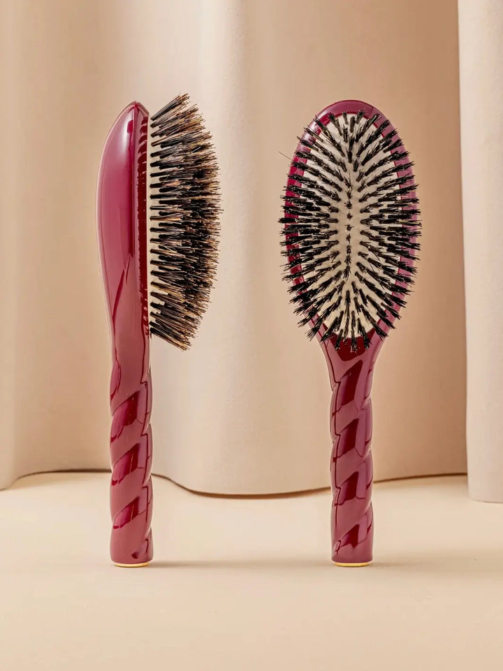 Front and side view of La Bonne Brosse N.01 The Shine & Care Hairbrush The Universal Brush in Cherry Red featuring a twisted ergonomic handle and natural boar bristles | Twentyseven Toronto