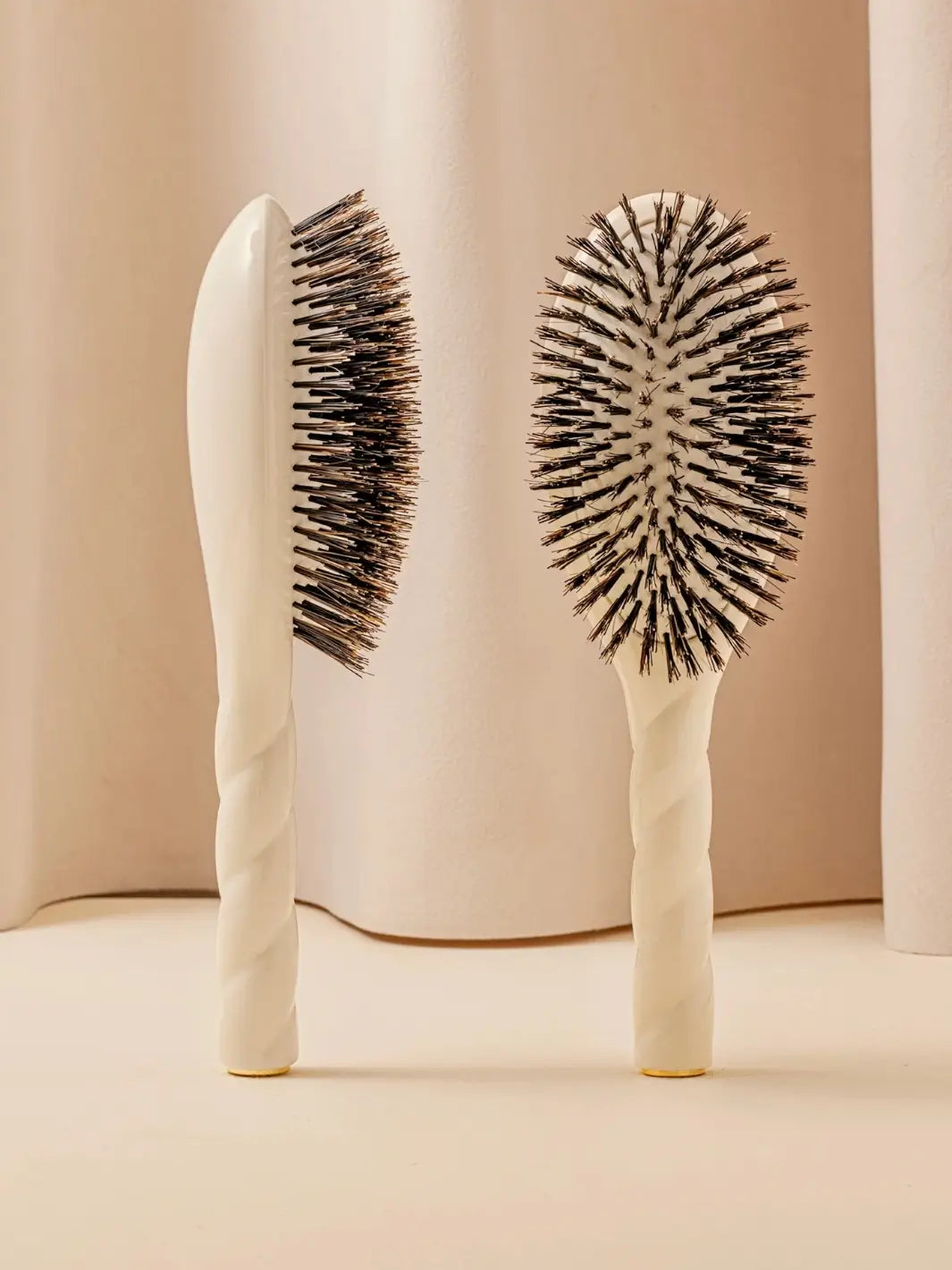 Front and side view of La Bonne Brosse N.01 The Shine & Care Hairbrush The Universal Brush in Creamy White featuring a twisted ergonomic handle and natural boar bristles | Twentyseven Toronto