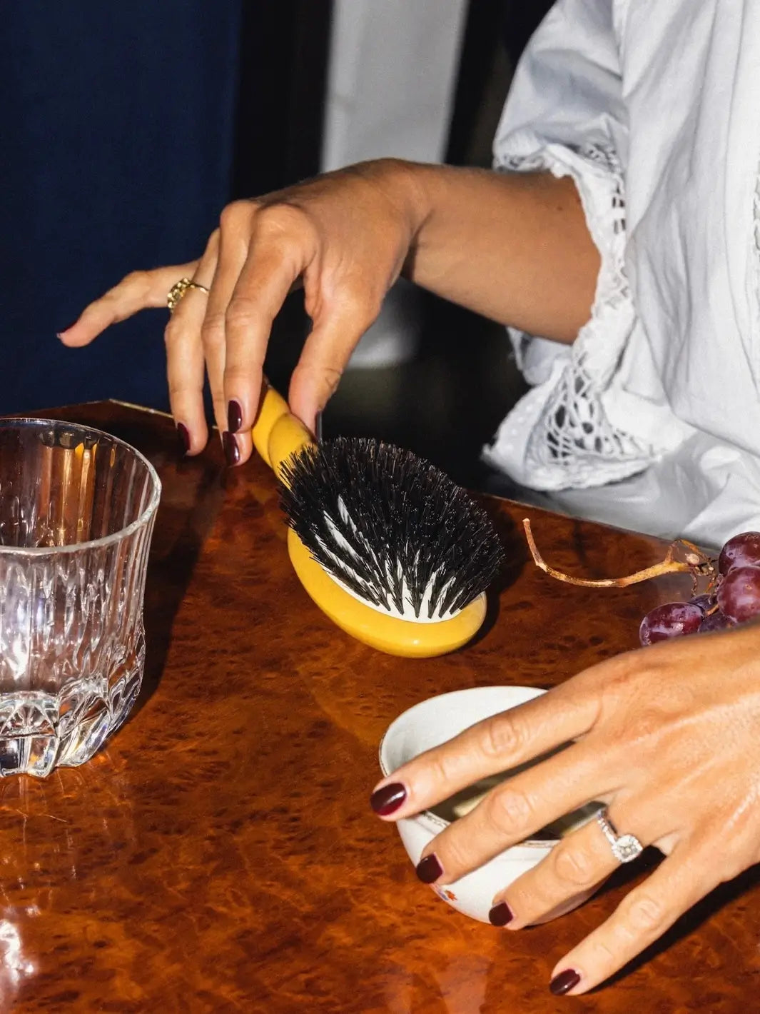 Person holding the La Bonne Brosse N.01 The Shine & Care Hairbrush The Universal Brush in Saffron Yellow resting on a polished wood surface | Twentyseven Toronto