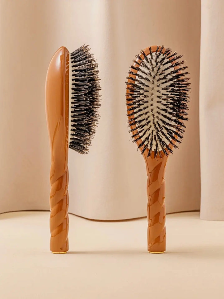 Front and side view of La Bonne Brosse N.01 The Shine & Care Hairbrush The Universal Brush in Terracotta featuring a twisted ergonomic handle and natural boar bristles | Twentyseven Toronto