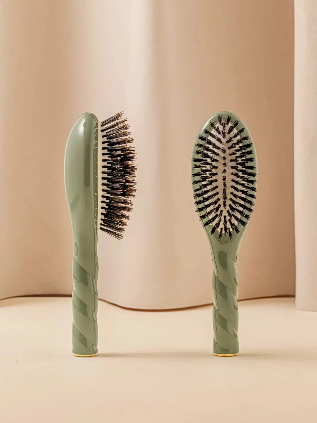 Front and side view of La Bonne Brosse N.01 Small The Shine & Care Hairbrush The Universal Brush in Almond Green featuring a twisted ergonomic handle and natural boar bristles | Twentyseven Toronto