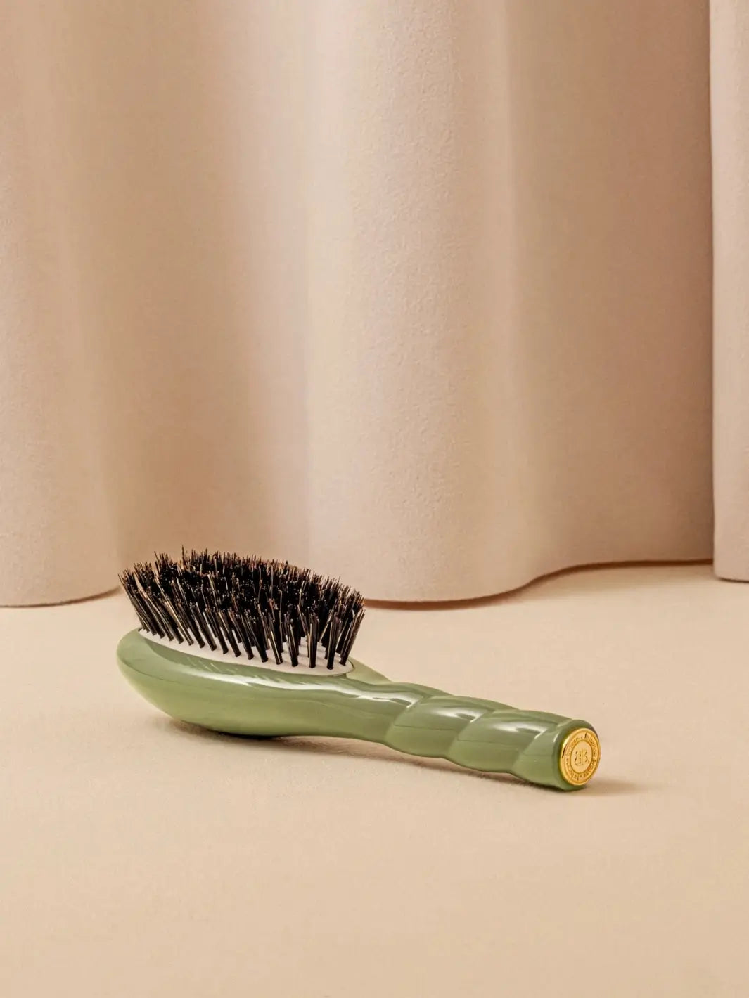 La Bonne Brosse N.01 Small The Shine & Care Hairbrush The Universal Brush in Almond Green resting on a neutral surface against a soft draped curtain background | Twentyseven Toronto
