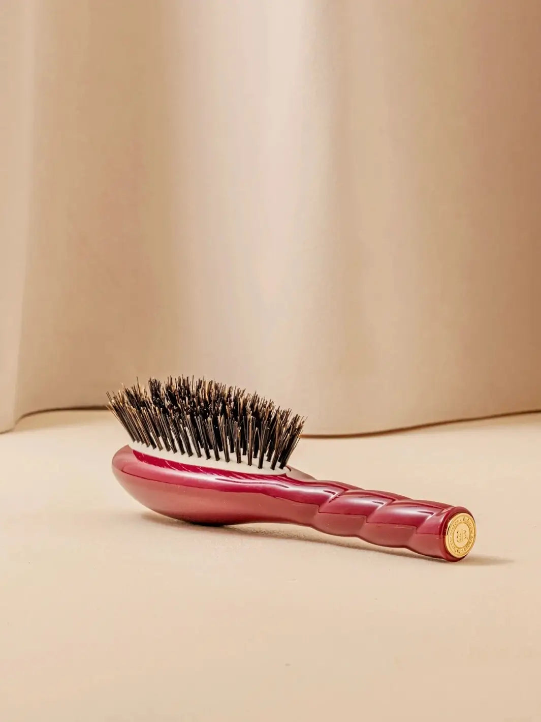 La Bonne Brosse N.01 Small The Shine & Care Hairbrush The Universal Brush in Cherry Red resting on a neutral surface against a soft draped curtain background | Twentyseven Toronto