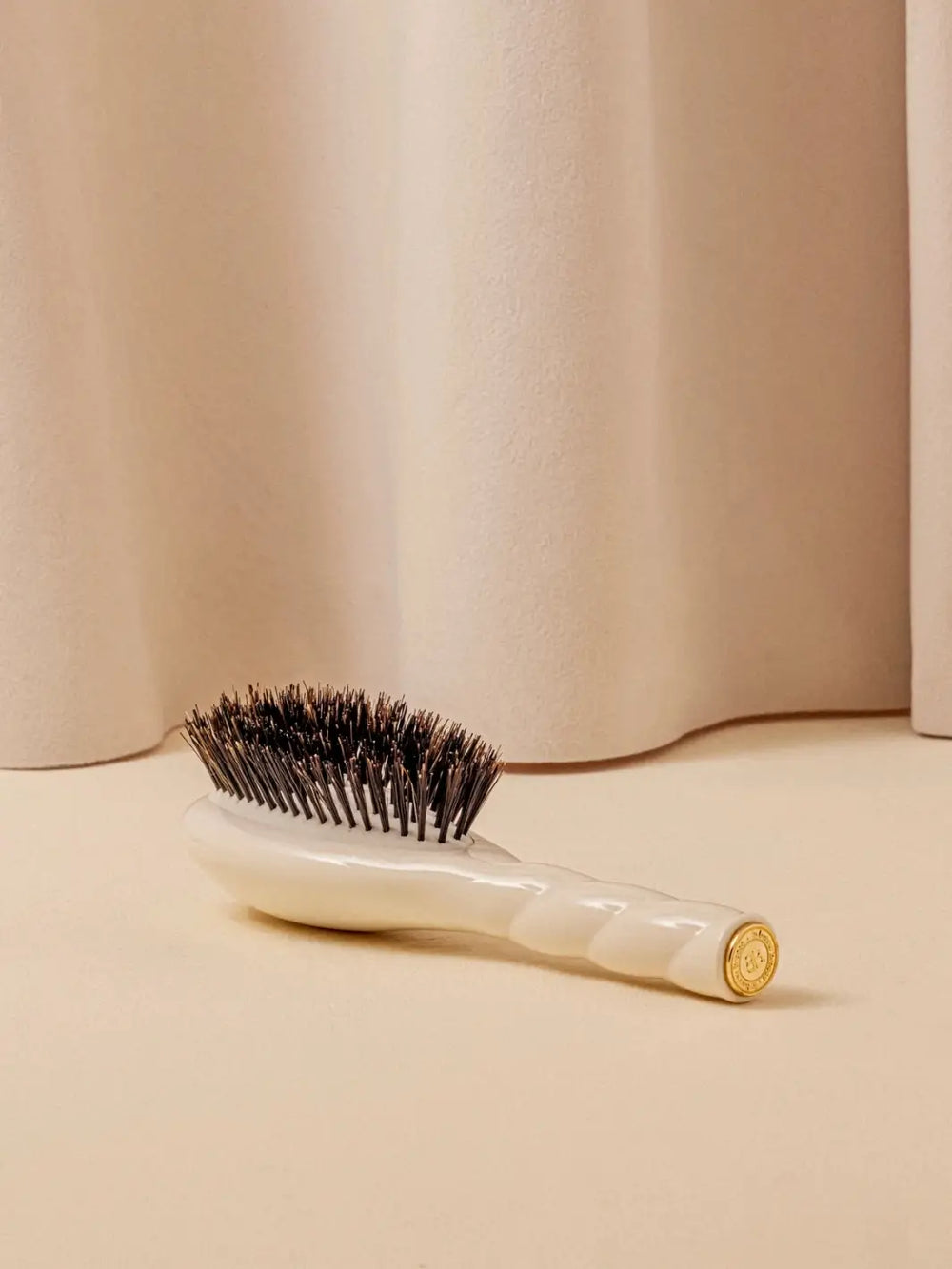 La Bonne Brosse N.01 Small The Shine & Care Hairbrush The Universal Brush in Creamy White resting on a neutral surface against a soft draped curtain background | Twentyseven Toronto