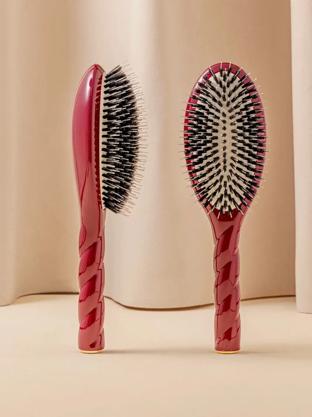 Front and side view of La Bonne Brosse N.02 Large The Essential Detangling & Conditioning Brush in Cherry Red featuring a twisted ergonomic handle and natural boar bristles | Twentyseven Toronto