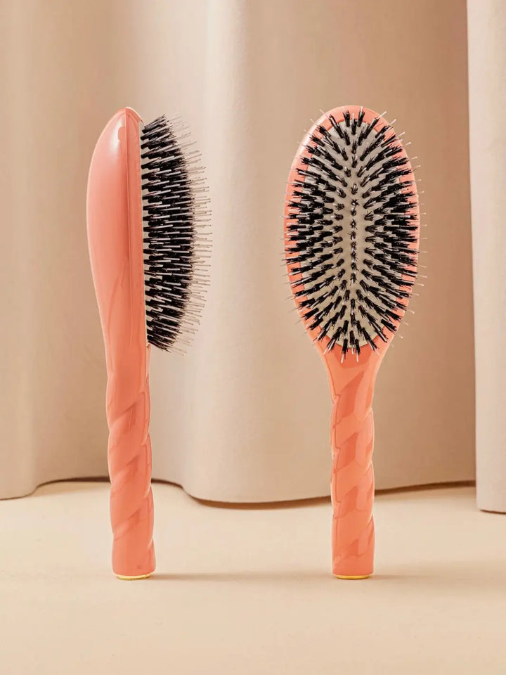 Front and side view of La Bonne Brosse N.02 Large The Essential Detangling & Conditioning Brush in Orange Coral featuring a twisted ergonomic handle and natural boar bristles | Twentyseven Toronto