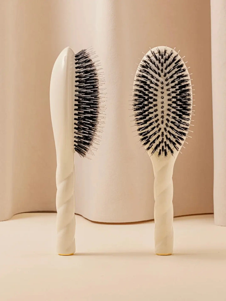 Front and side view of La Bonne Brosse N.02 Large The Essential Detangling & Conditioning Brush in Creamy White featuring a twisted ergonomic handle and natural boar bristles | Twentyseven Toronto