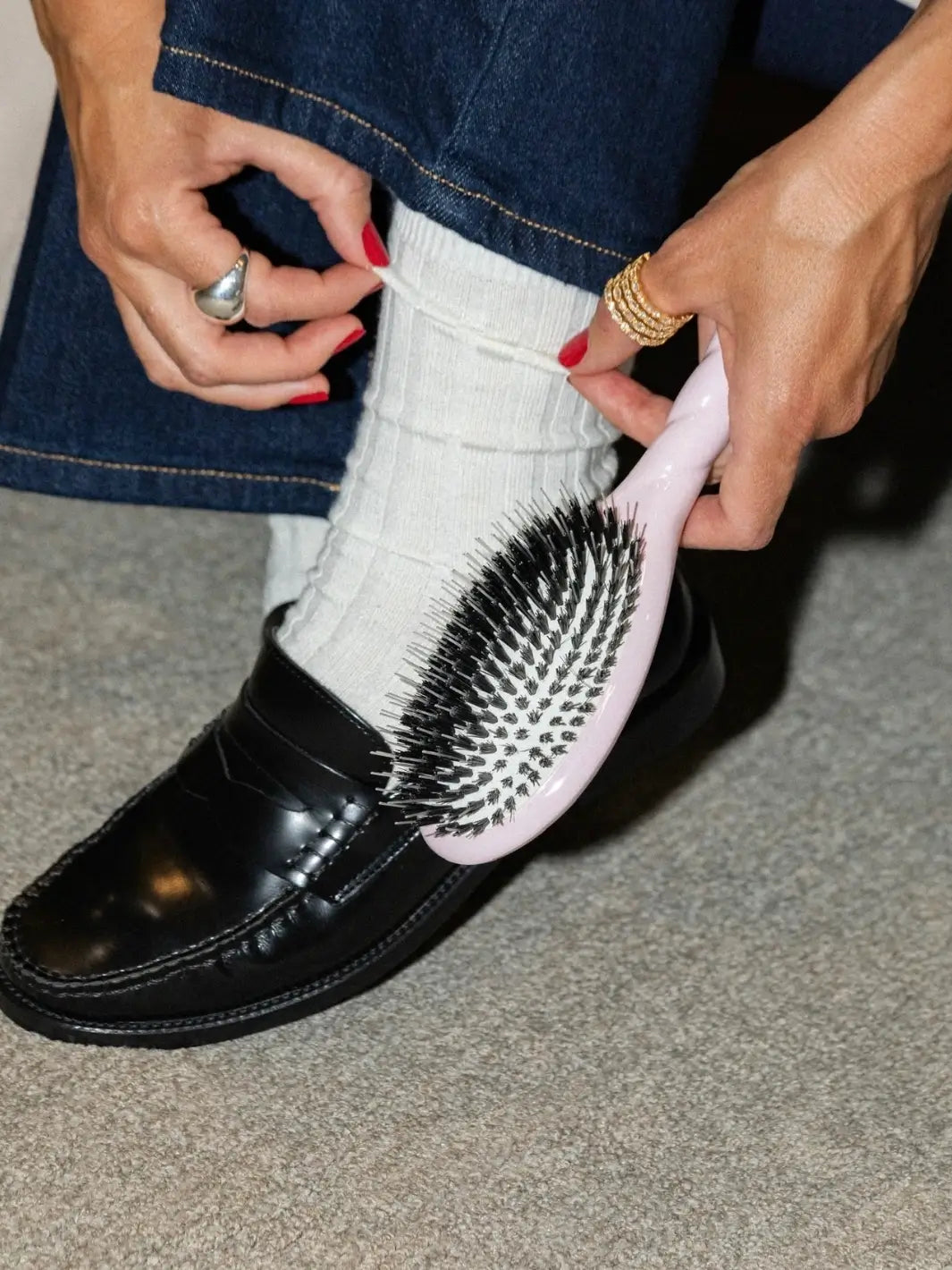 Person wearing loafers and white socks holds the La Bonne Brosse N.03 Small The Essential Softness & Sensitive Scalp Brush in Lilac Pink | Twentyseven Toronto