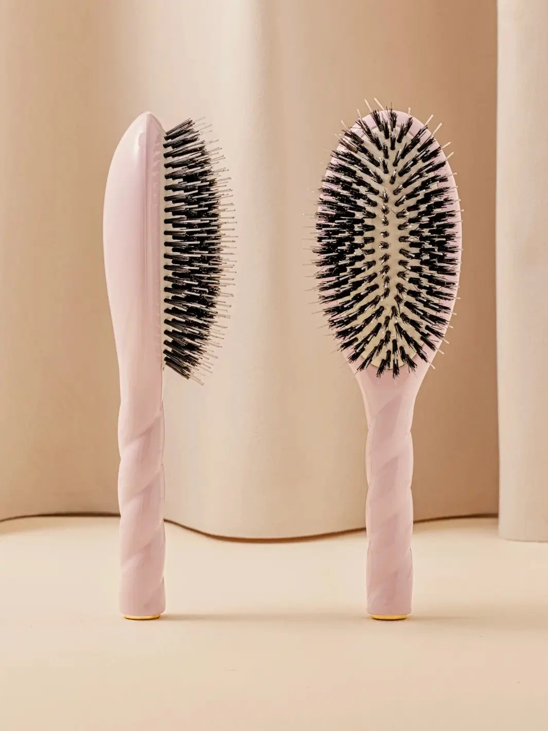 Front and side view of La Bonne Brosse N.02 Large The Essential Detangling & Conditioning Brush in Lilac Pink featuring a twisted ergonomic handle and natural boar bristles | Twentyseven Toronto