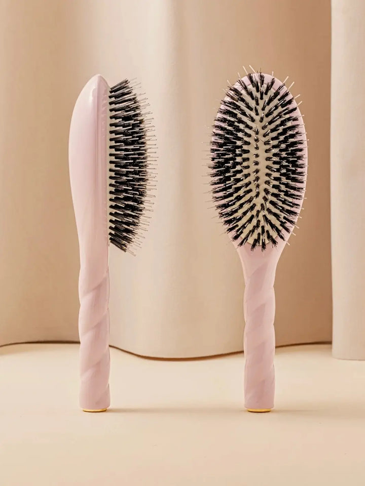 Front and side view of La Bonne Brosse N.02 Large The Essential Detangling & Conditioning Brush in Lilac Pink featuring a twisted ergonomic handle and natural boar bristles | Twentyseven Toronto