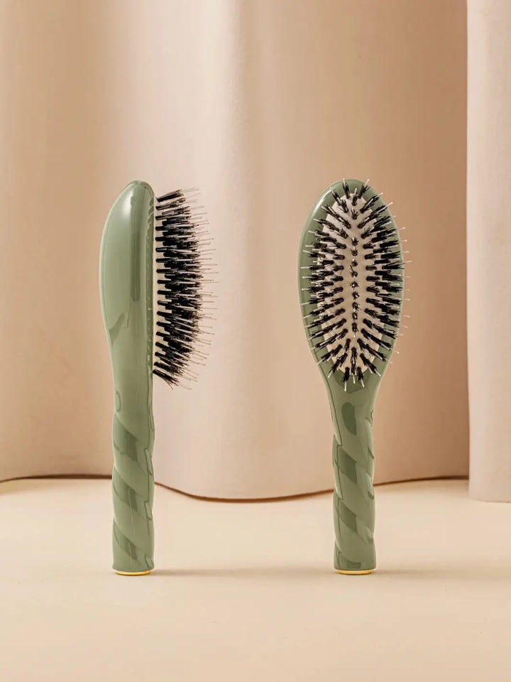 Front and side view of La Bonne Brosse N.02 Small The Essential Detangling & Conditioning Brush in Almond Green featuring a twisted ergonomic handle and natural boar and nylon bristles | Twentyseven Toronto