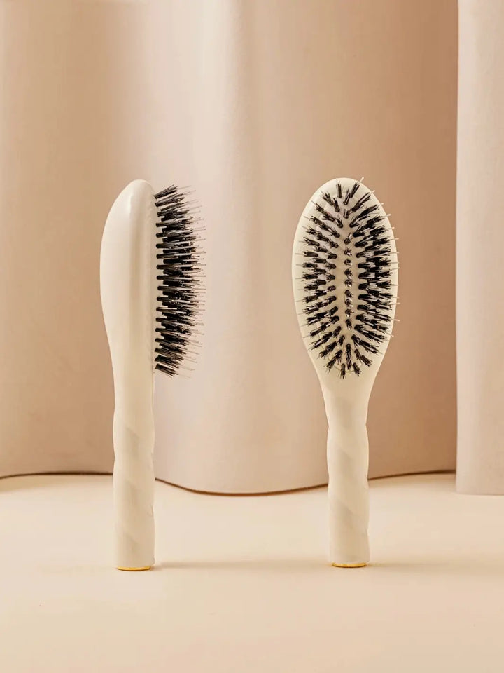 Front and side view of La Bonne Brosse N.02 Small The Essential Detangling & Conditioning Brush in Creamy White featuring a twisted ergonomic handle and natural boar and nylon bristles | Twentyseven Toronto