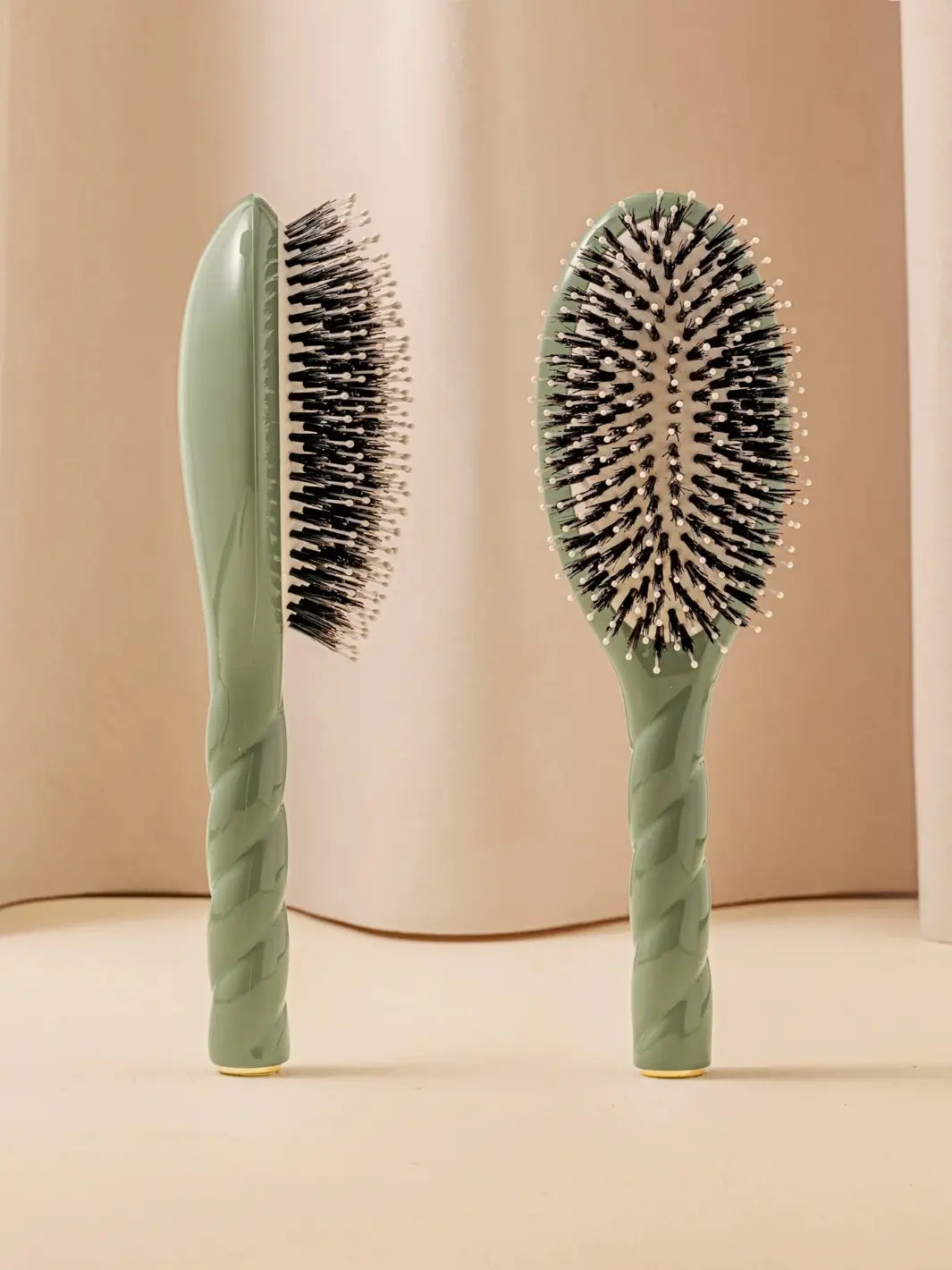Front and side view of La Bonne Brosse N.03 Large The Essential Softness & Sensitive Scalp Brush in Almond Green featuring a twisted ergonomic handle and natural boar bristles | Twentyseven Toronto