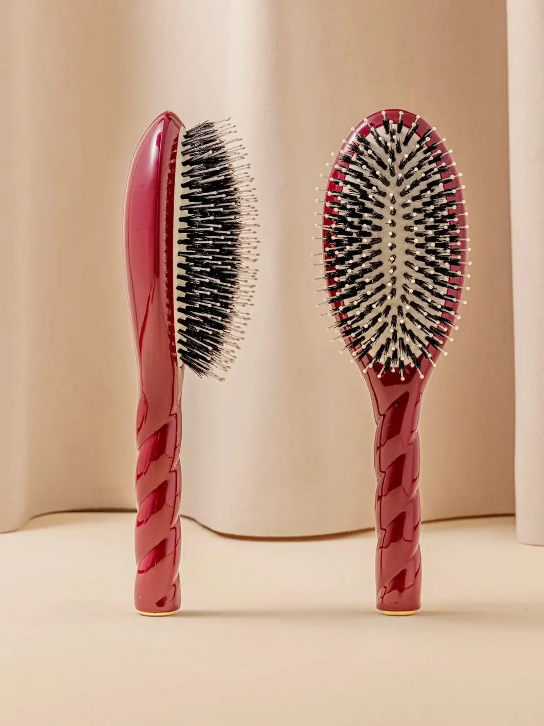 Front and side view of La Bonne Brosse N.03 Large The Essential Softness & Sensitive Scalp Brush in Cherry Red featuring a twisted ergonomic handle and natural boar bristles | Twentyseven Toronto