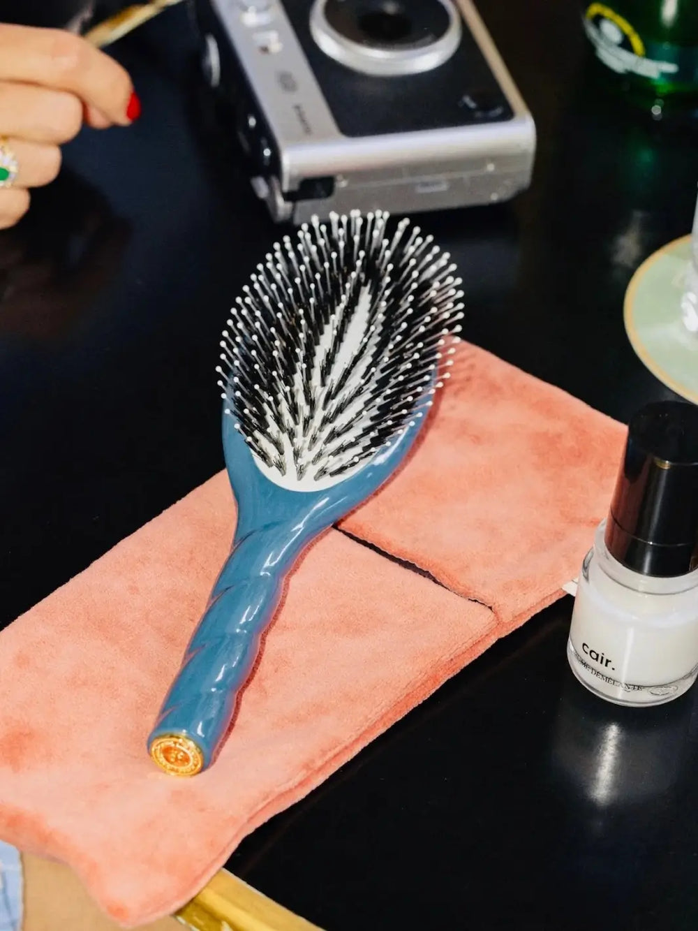 The La Bonne Brosse N.03 Large The Essential Softness & Sensitive Scalp Brush in Ink Blue resting on a plush pink cloth alongside a camera and Cair Haircare products | Twentyseven Torotno