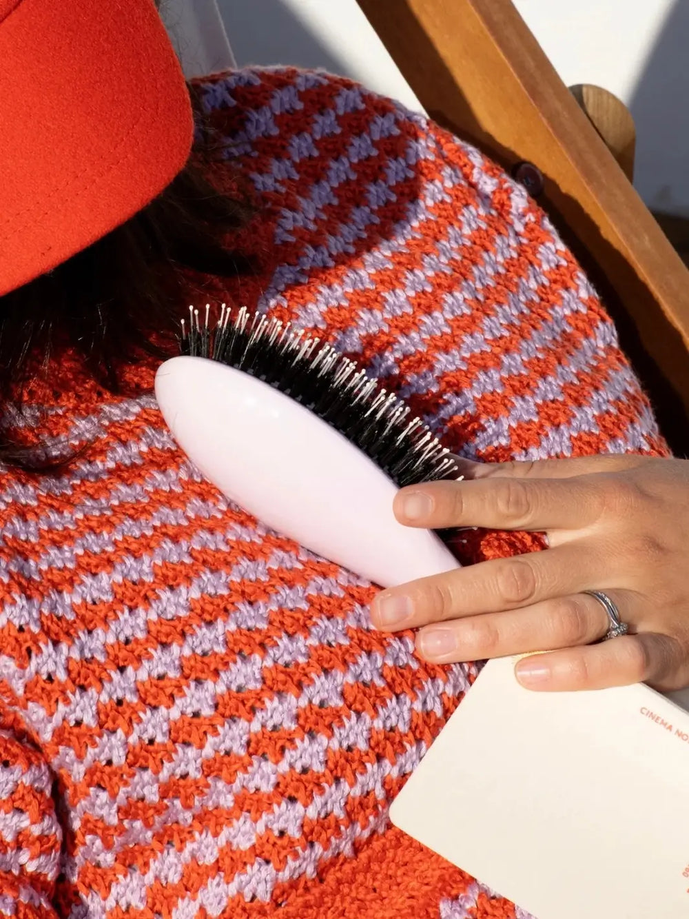 A person holding the La Bonne Brosse N.03 Large The Essential Softness & Sensitive Scalp Brush in Lilac Pink against a vibrant orange and lilac patterned sweater | Twentyseven Toronto