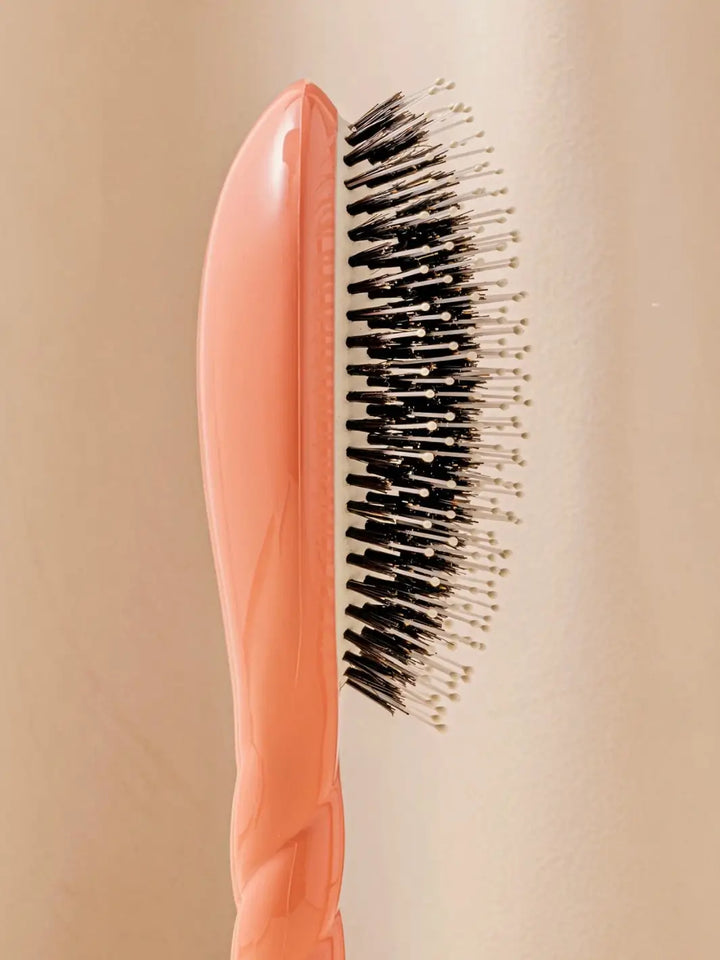 Close-up side image highlights the tiered bristle design of La Bonne Brosse N.03 Large The Essential Softness & Sensitive Scalp Brush in Orange Coral | Twentyseven Toronto