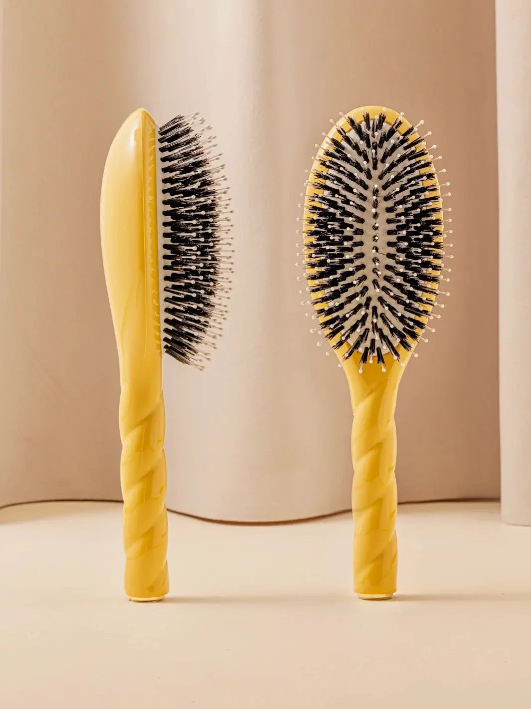 Front and side view of La Bonne Brosse N.03 Large The Essential Softness & Sensitive Scalp Brush in Saffron Yellow featuring a twisted ergonomic handle and natural boar bristles | Twentyseven Toronto