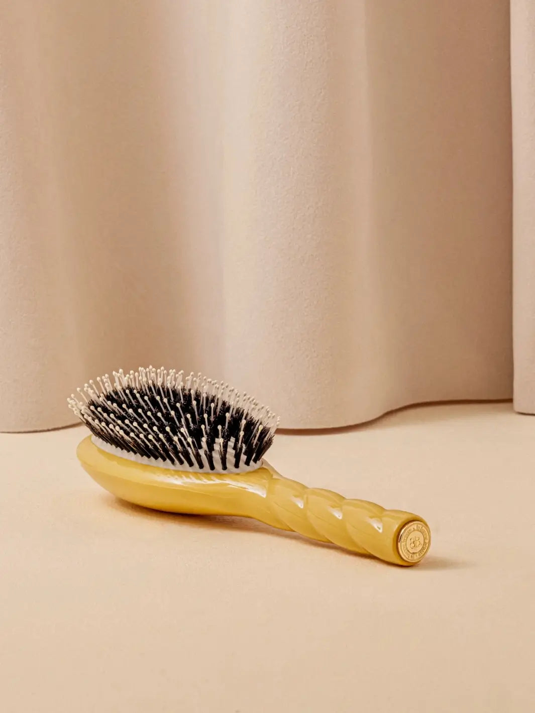 La Bonne Brosse N.03 Large The Essential Softness & Sensitive Scalp Brush in Saffron Yellow laying on a beige surface against a neutral curtain | Twentyseven Toronto