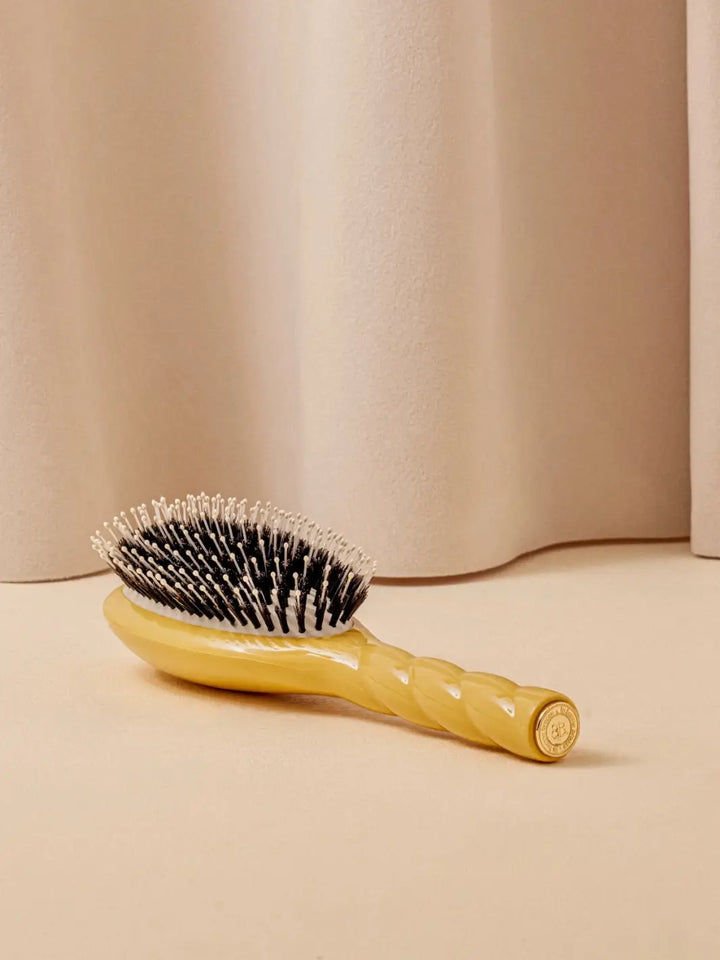 La Bonne Brosse N.03 Large The Essential Softness & Sensitive Scalp Brush in Saffron Yellow laying on a beige surface against a neutral curtain | Twentyseven Toronto