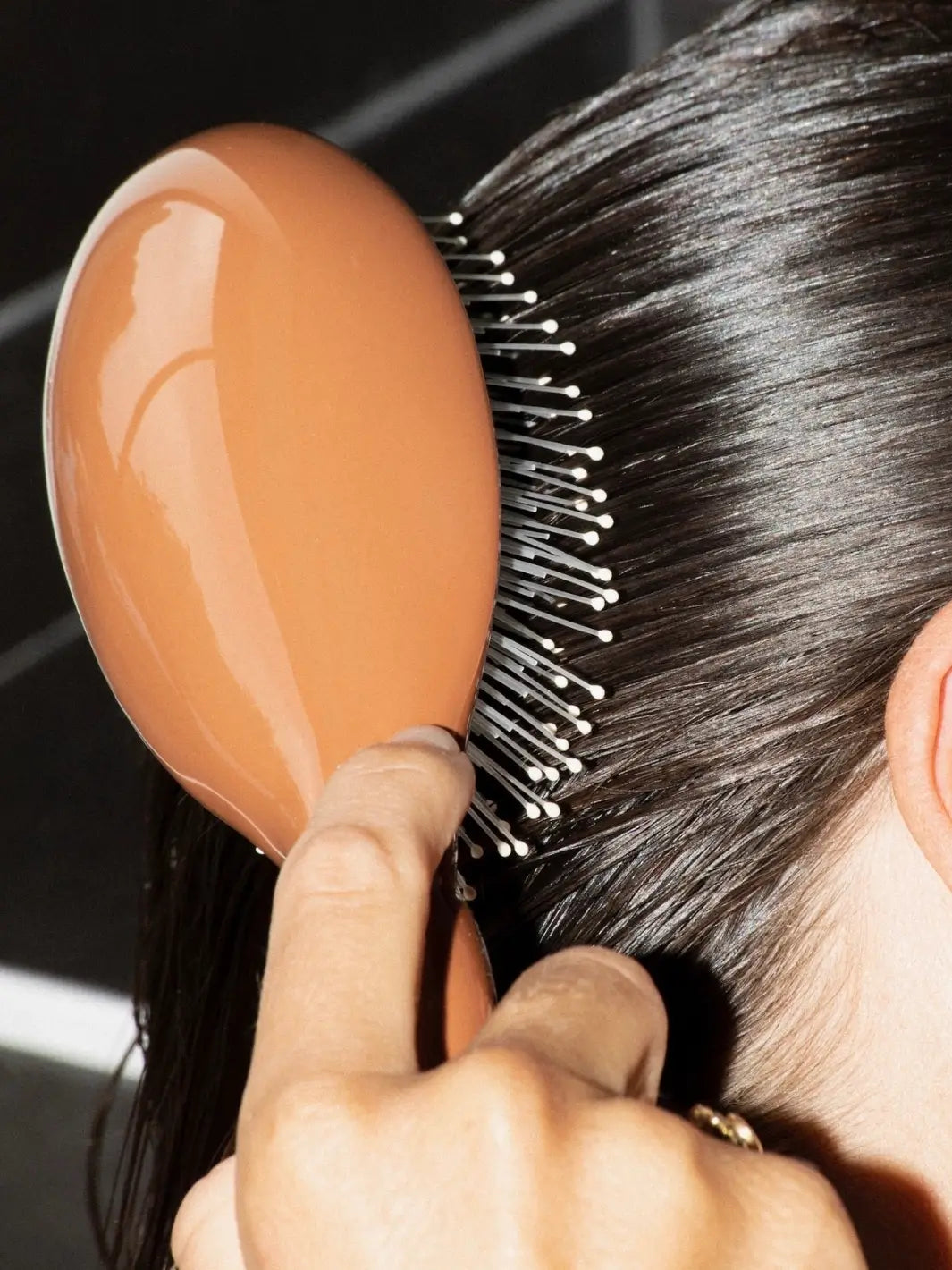 Person using the La Bonne Brosse N.03 Large The Essential Softness & Sensitive Scalp Brush in Terracotta to smooth through sleek, dark hair | Twentyseven Toronto