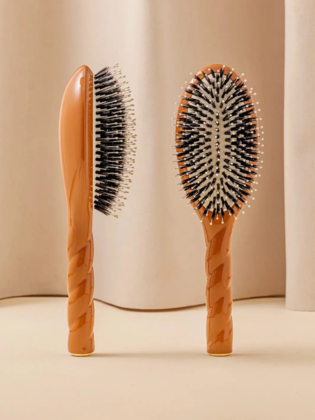Front and side view of La Bonne Brosse N.03 Large The Essential Softness & Sensitive Scalp Brush in Terracotta featuring a twisted ergonomic handle and natural boar bristles | Twentyseven Toronto
