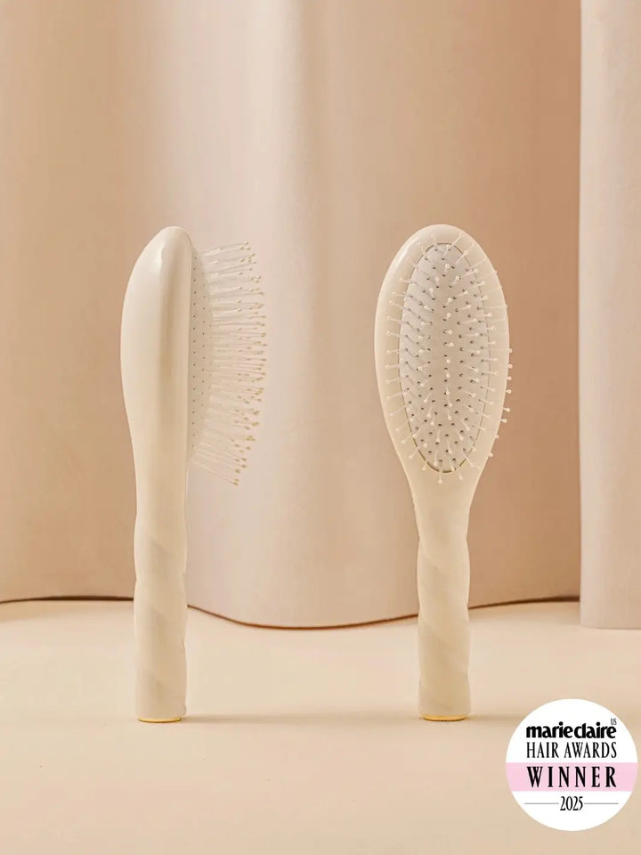 Front and side view of La Bonne Brosse N.04 Small The Detangling & Massaging Miracle Brush in Creamy White featuring a twisted ergonomic handle and nylon bristles | Twentyseven Toronto