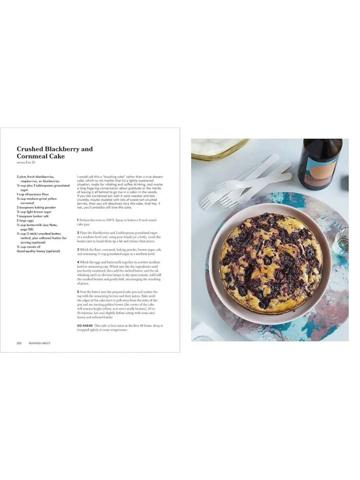 A page layout displays a recipe for a crushed blackberry and cornmeal cake alongside an image of the freshly baked round cake on a serving plate, from Nothing Fancy: Unfussy Food for Having People Over by Alison Roman | Twentyseven Toronto