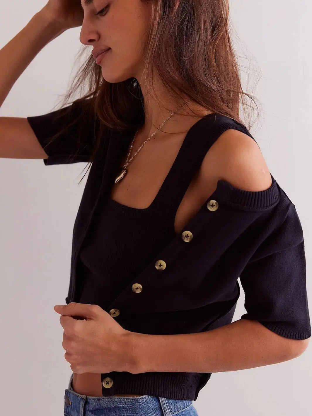 A side-angle view shows a model wearing the Free People We The Free NY Twosie - Black with the button-down short-sleeve cardigan pulled off one shoulder to reveal the matching tank top underneath | Twentyseven Toronto