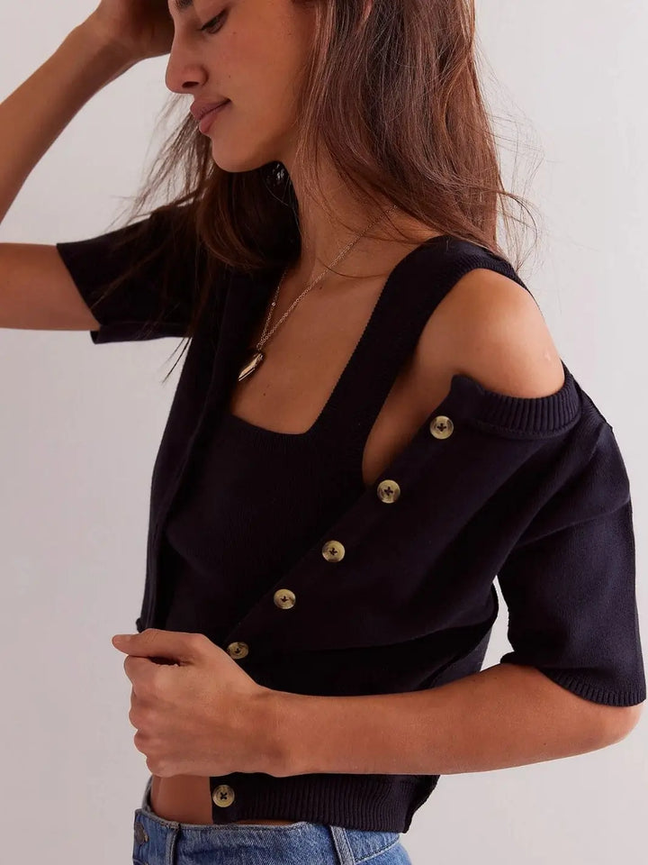 A side-angle view shows a model wearing the Free People We The Free NY Twosie - Black with the button-down short-sleeve cardigan pulled off one shoulder to reveal the matching tank top underneath | Twentyseven Toronto