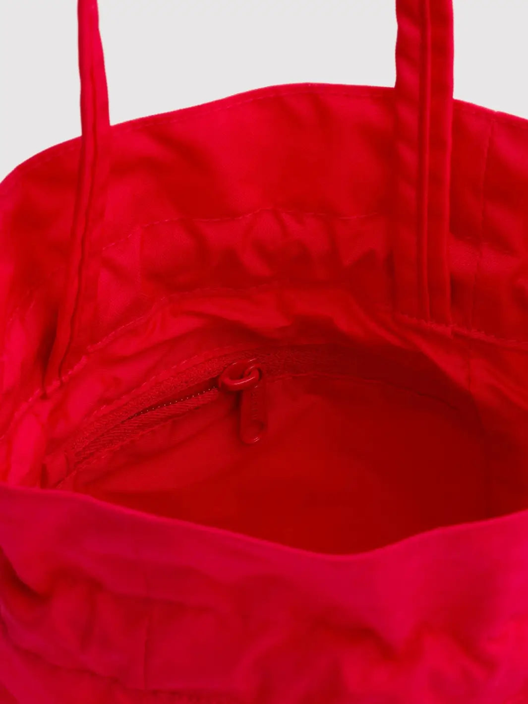 Close-up image shows the vibrant red interior and internal zippered pocket of the BAGGU Nylon Drawstring Bag in Candy Apple | Twentyseven Toronto