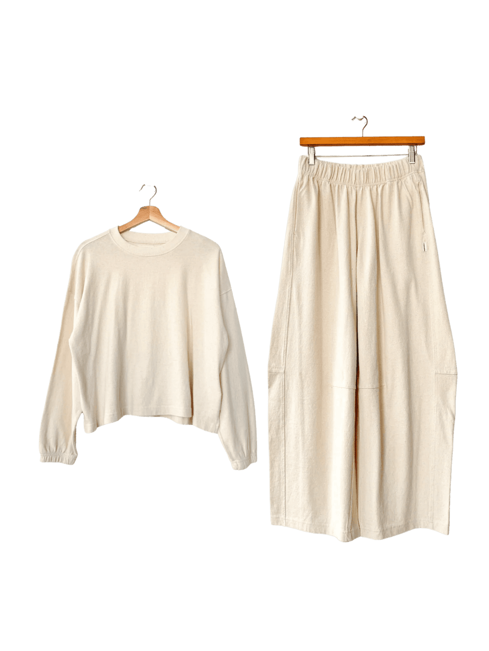 White 'Naturelle Tee' long-sleeve top and white wide leg 'Bare Pants' in 'Naturel' from Le Bon Shoppe on hangers against a transparent background | Twentyseven Toronto