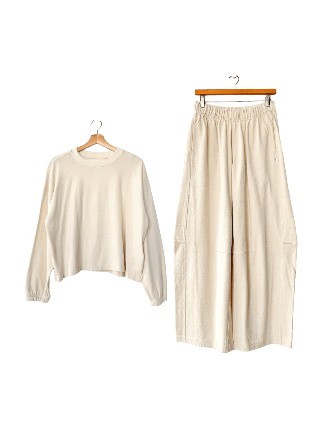 White 'Naturelle Tee' long-sleeve top and white wide leg 'Bare Pants' in 'Naturel' from Le Bon Shoppe on hangers against a transparent background | Twentyseven Toronto