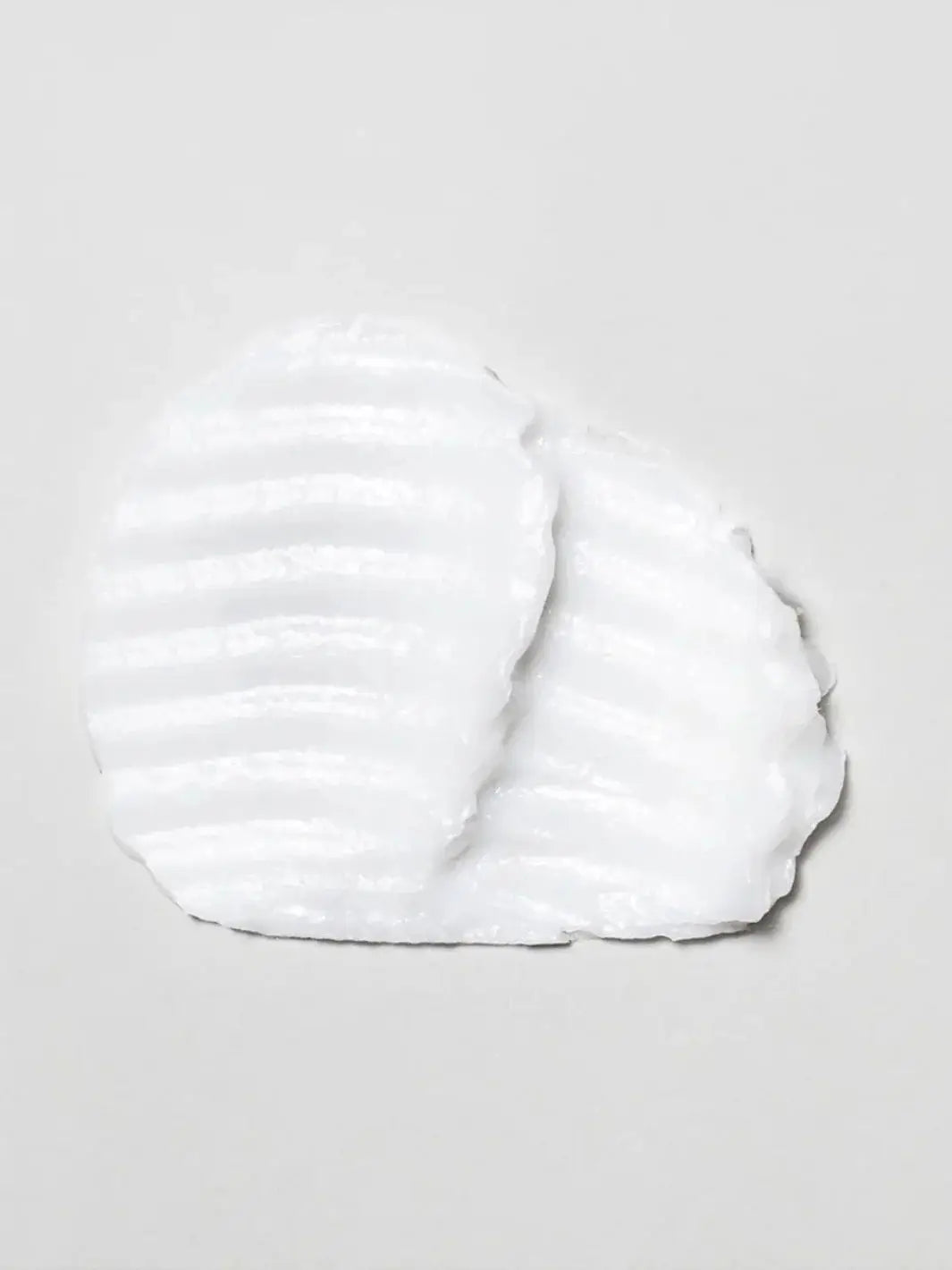 A textured smear of the thick, white Davines OI Hair Butter Mask is shown against a light grey background | Twentyseven Toronto