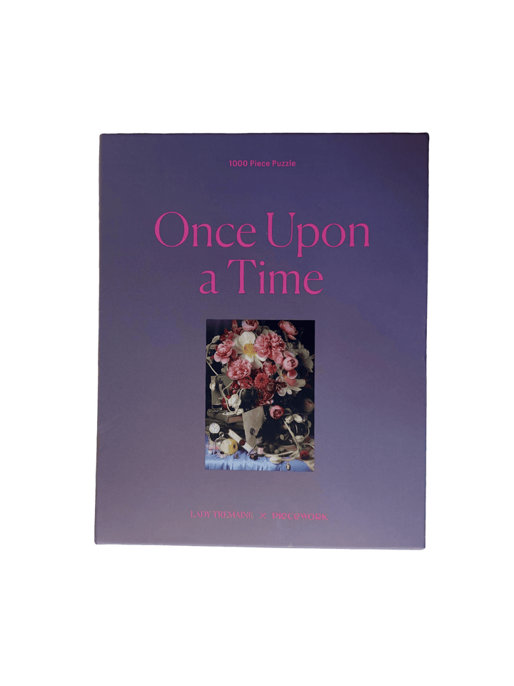 Purple puzzle packaging titled 'Once Upon a Time' 1000 piece puzzle by Piecework Puzzles with a floral photograph on a transparent background | Twentyseven Toronto