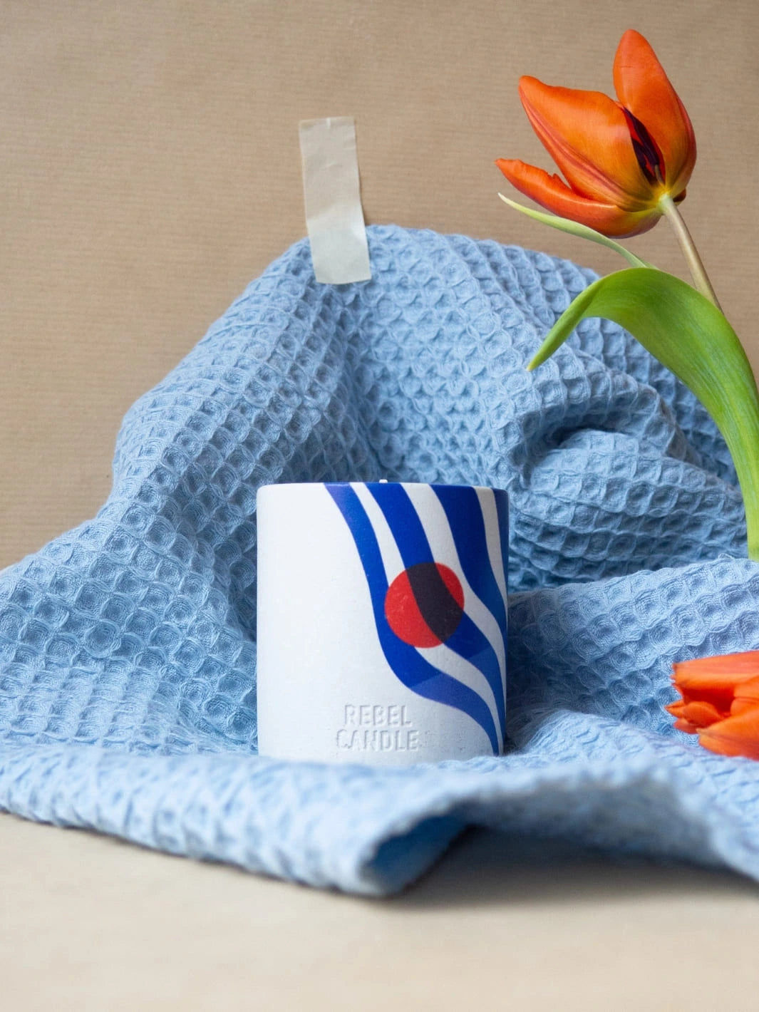 Maison Matine Onde Urbaine Scented Candle with colorful design on a blue textured towel with a tulip 160g  | Twentyseven Toronto