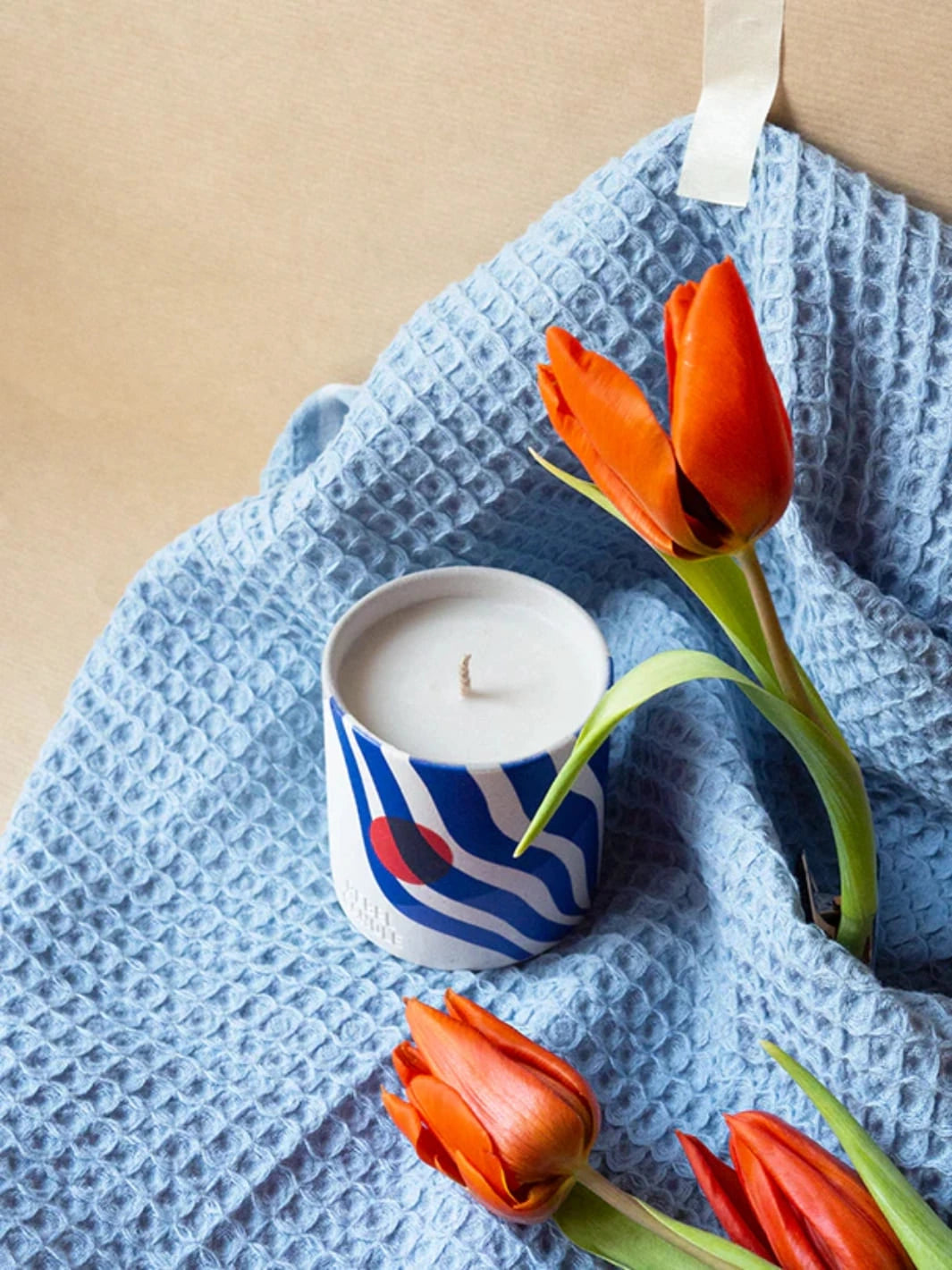 Colourful Maison Matine Onde Urbaine Scented Candle on a blue textured towel with orange tulips 160g | Twentyseven Toronto