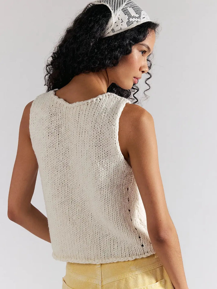 A rear three-quarter view shows a model looking over her shoulder, highlighting the open-stitch side detailing and back of the Free People Opal Knit Tank in Whisper White | Twentyseven Toronto