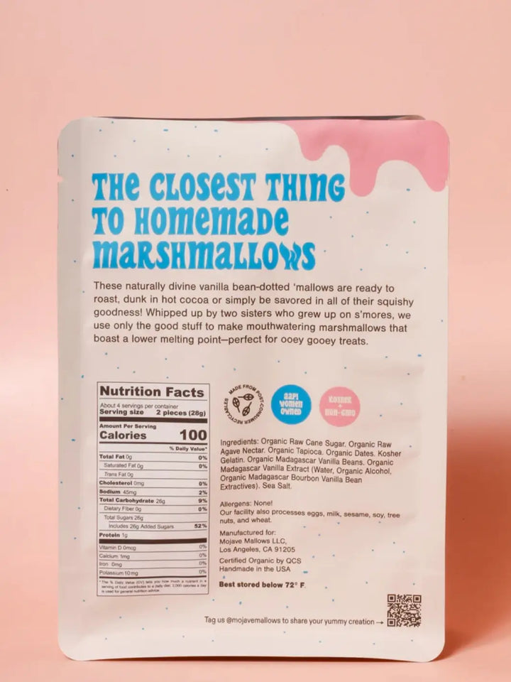 The back of a Mojave Mallows Organic Vanilla Bean Marshmallows package showing the nutrition facts, ingredients list, and brand story against a solid pink background | Twentyseven Toronto