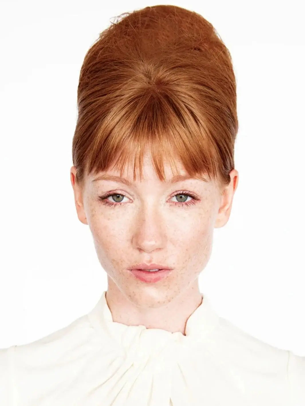 A model with red hair showcases a sleek, high-volume beehive updo styled using R+Co OUTER SPACE Flexible Hairspray | Twentyseven Toronto