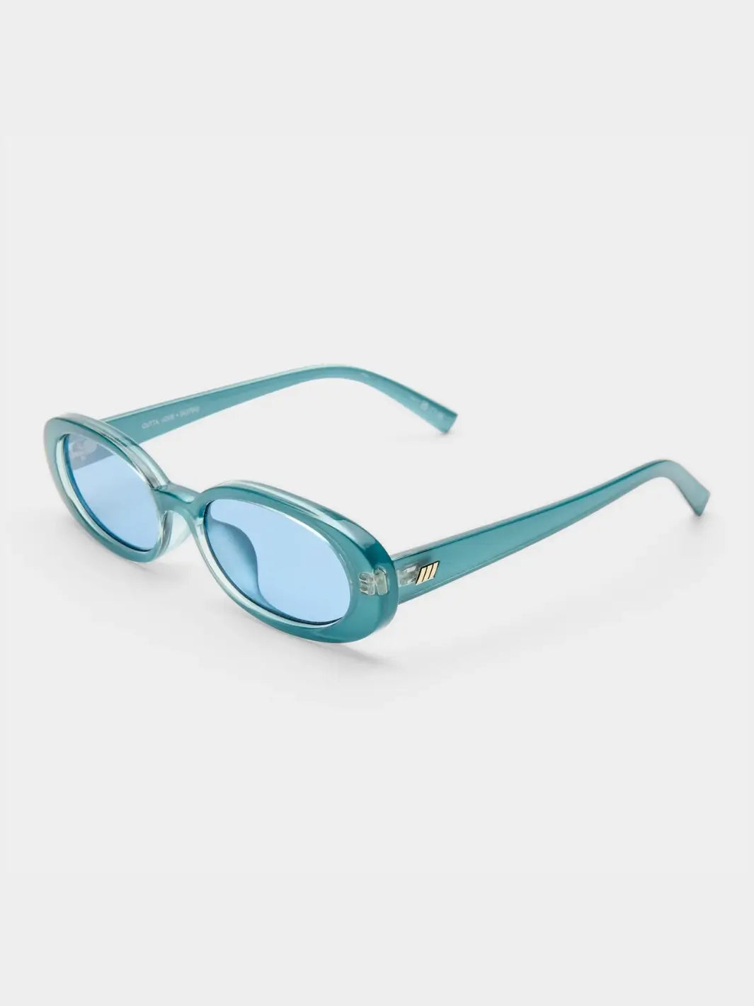A three-quarter studio shot of the translucent teal Le Specs Sunglasses Outta Love + in Blue Pearl resting on a white surface | Twentyseven Toronto