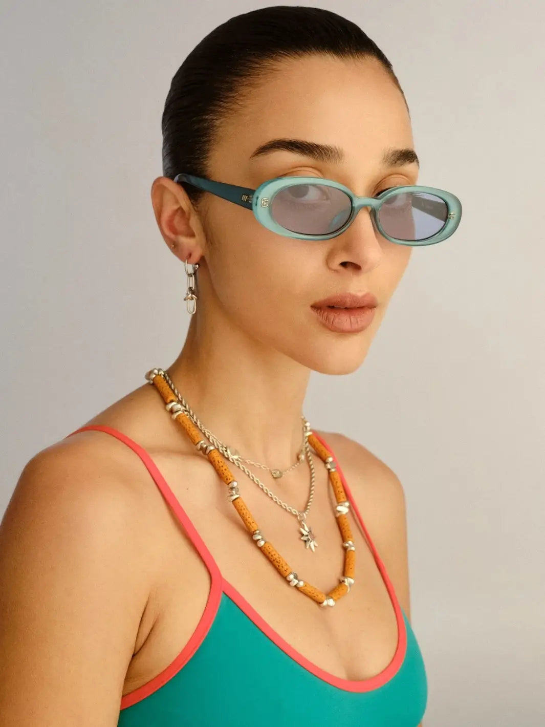 A portrait of a woman looking forward while wearing the oval-framed Le Specs Sunglasses Outta Love + in Blue Pearl | Twentyseven Toronto